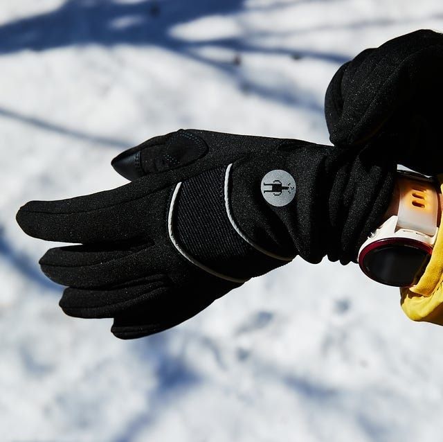 Svart vinterhandske och handledsburen enhet mot snötäckt mark